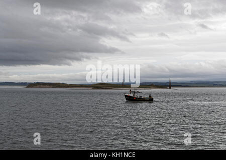 Shell fishing vessel Britannia II operating off Guile Island at Holy Island with the Old Law navigation aids in the background Stock Photo