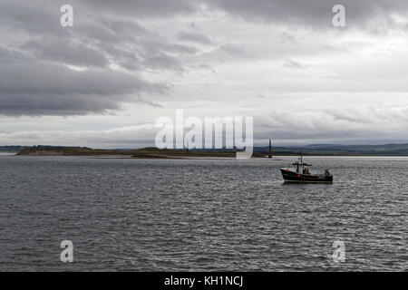 Shell fishing vessel Britannia II operating off Guile Island at Holy Island with the Old Law navigation aids in the background Stock Photo