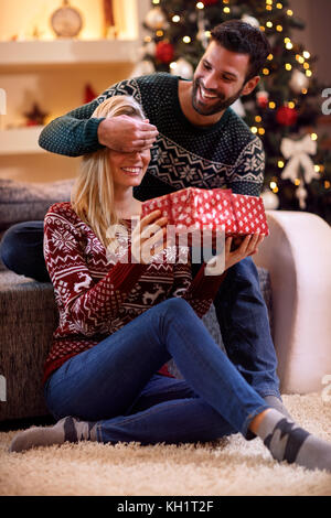 happy man surprises woman with Christmas gift Stock Photo