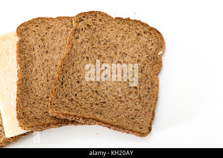 Whole grain sandwich bread slices with one white slice, on white background. Stock Photo