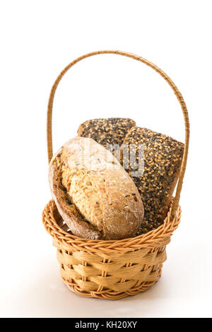 Whole wheat sandwich buns with seeds in wicker basket, on white background. Stock Photo