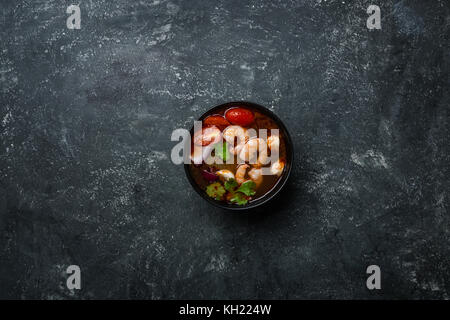 Spicy Thai soup Tom Yam with seafoodon on a vintage colored background. Top view. Stock Photo