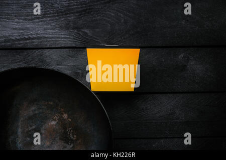 Asian Wok - Traditional oriental pan on a black wooden background. With a box for noodles. Top view. Stock Photo