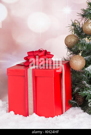 Red gift box next to a Christmas tree with a colorful background Stock Photo