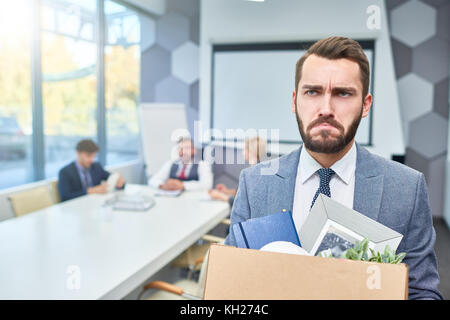 Portrait of sad bearded businessman holding box of personal belongings being fired from work in company, copy space Stock Photo