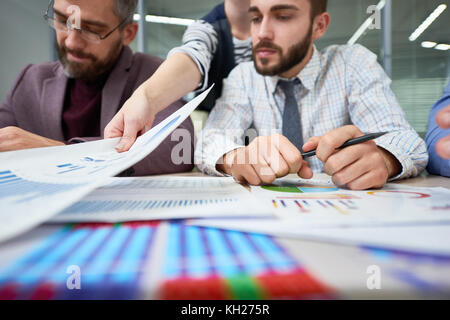 Group of busy business people sitting at table with charts and graphs analyzing financial and marketing statistics for annual report Stock Photo