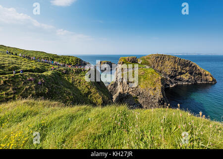 Thousands of tourists visiting Carrick-a-Rede Rope Bridge in County Antrim of Northern Ireland, hanging 30m above rocks and spanning 20m, linking main Stock Photo