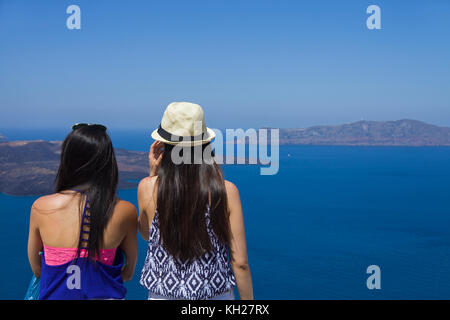 Two girls enjoying view from the crater edge path at Thira to Caldera and Nea Kameni island, Santorini, Cyclades, Greece, Mediterranean Sea, Europe Stock Photo