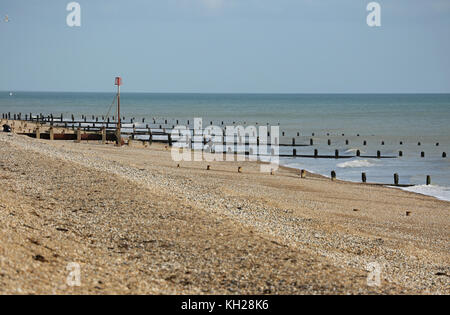 View along deserted Bognor beach, southern England, on a sunny, winter day. Shows wooden breakwater structures installed to prevent coastal erosion. Stock Photo