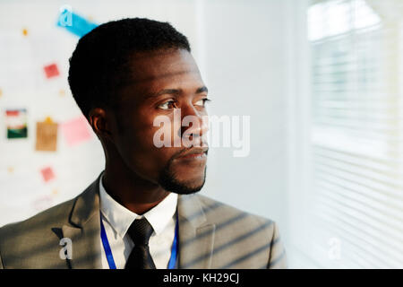 Serious African-american businessman looking through window in office Stock Photo