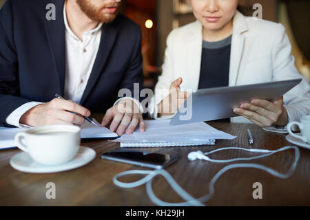 Young modern brokers analyzing online information at meeting Stock Photo