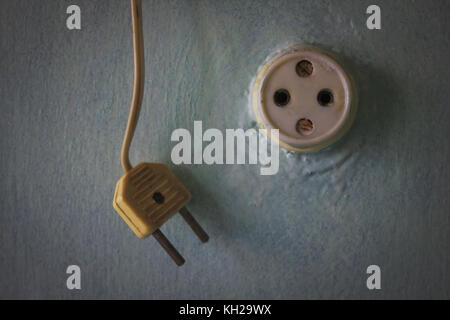 Vintage plug on the wire hangs next to the old socket Stock Photo