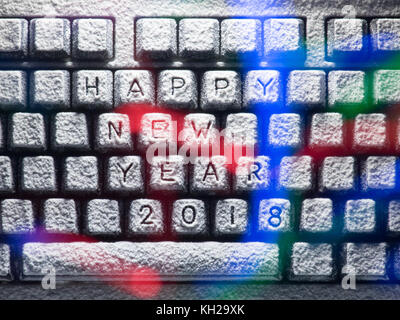 computer keyboard covered with snow with title happy new year 2018 lit by colorful lights Stock Photo