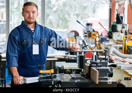 Portrait of young worker posing looking at camera with machine units in modern factory showroom , copy space Stock Photo