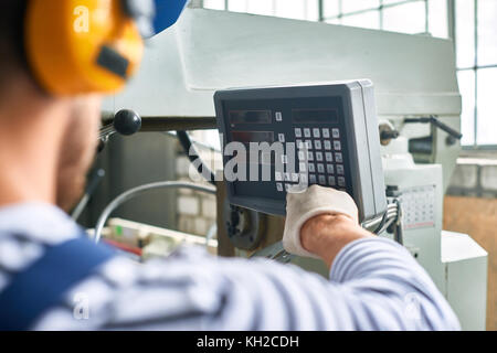 Closeup of worker pushing buttons on  electronic control panel while operating machine units at modern factory Stock Photo