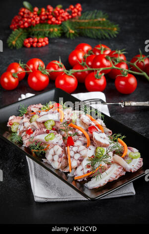 Plate with octopus salad on table decorated for winter holidays. Stock Photo