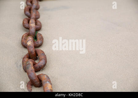 Rusty old boat chain on a sandy beach with a shallow depth of field Stock Photo