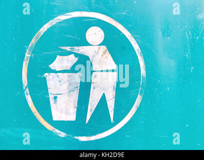 Dirty old white sign on green background showing person putting litter into a bin. Putting trash into a trash can sign Stock Photo