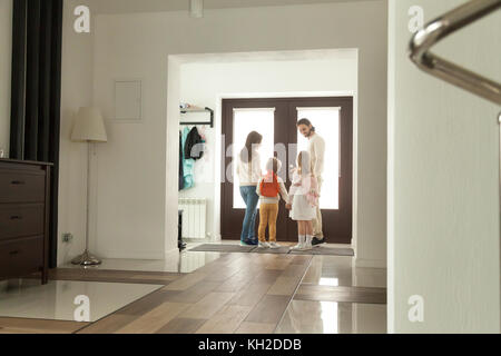 Happy family going out standing in hallway opening door, parents leaving home with kids holding son and daughter hands, mother father taking children  Stock Photo
