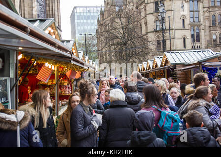 Manchester Christmas Market in Albert Square Manchester UK.  Crowds of people Christmas shopping down the tighlty packed corridors of Market Stalls. Stock Photo