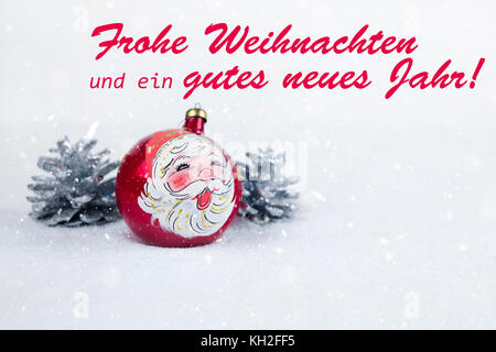 Group of colorful Christmas ball with drawing of Santa Claus and pines with text in German 'Frohe Weihnachten und ein gutes neues Jahr' in white snow 