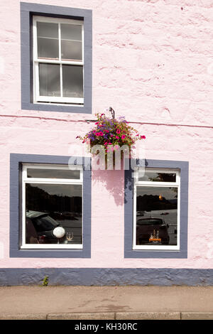 windows with wrought iron bars painted black with pots of red flowers on the windowsill and whitewashed wall Stock Photo