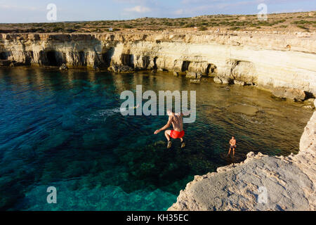 Young male tourist jumps from the cliff top, Cape Greco seacaves, Cyprus Stock Photo