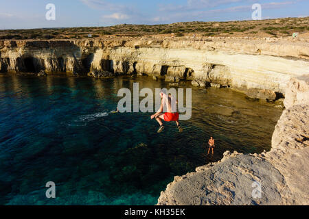 Young male tourist jumps from the cliff top, Cape Greco seacaves, Cyprus Stock Photo