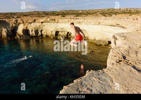 Young male tourist jumps from the cliff top, Cape Greco seacaves, Cyprus Stock Photo