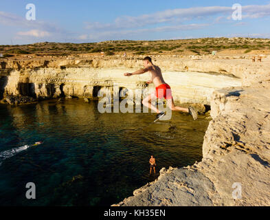 Young male tourist jumps from the cliff top, Cape Greco seacaves, Cyprus Stock Photo