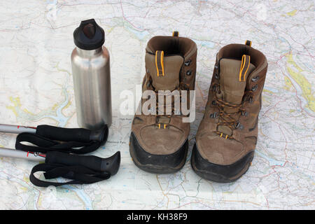 Hiking gear. Walking poles, water flask and trekking boots set on a map in which the words 'National Park' are visible. No brand names are visible. Stock Photo