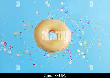 one flying sweet doughnut in glaze with sprincles on blue Stock Photo