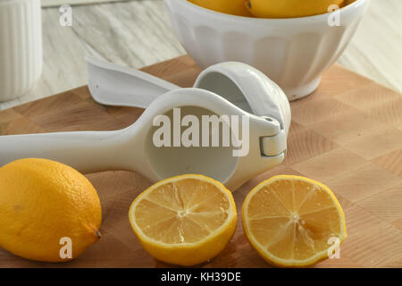 Fresh Organic Sliced Lemons-White and Yellow with citrus hand-held juicer, light and bright on a wooden cutting board Stock Photo