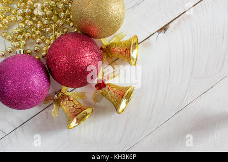 Christmas Decoration, chains, bells and colorful reflective balls, on top of a white wood surface and white background Stock Photo