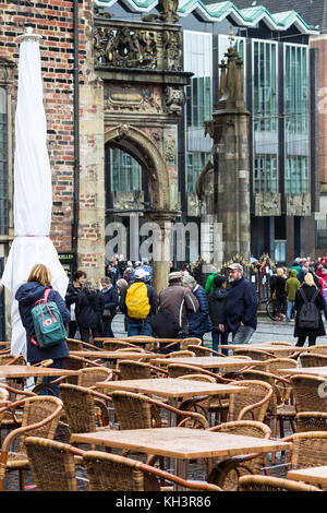 BREMEN, GERMANY - SEPTEMBER 16, 2017: tourists and table of outdoor cafe on Bremer Marktplatz (Bremen Market Square) in autumn rain. The square is sit Stock Photo