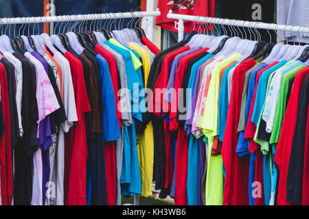 Fashionable clothing on hangers in shop Stock Photo