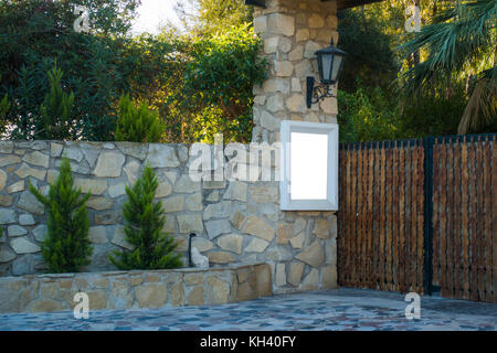 High brick wall with wooden gates shielding garden and large house on