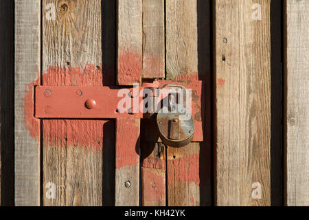 Detail of rusted metal lock on battened timber gate to a warehouse Stock Photo