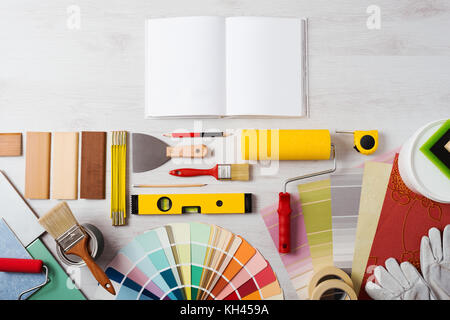 DIY training open manual with work tools, color swatches and painting rollers at bottom, top view Stock Photo