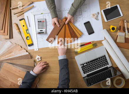 Interior designer showing wood swatches to his customer, laptop, tools and house projects on desktop top view Stock Photo