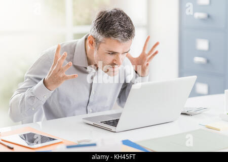 Angry frustrated office worker having problems with his laptop and connection, computer problems and troubleshooting concept Stock Photo