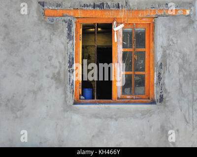 Orange window on a cement gray wall, wooden vintage frames and dirty glass. Stock Photo