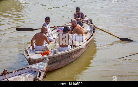 Priests on a wooden boat on the Ganges river for performing certain Hindu rituals as part of a daily worship routine at Varanasi India. Stock Photo