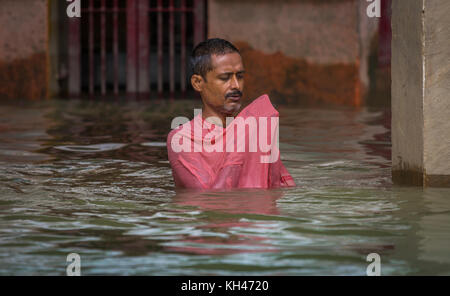 Man in his morning prayers half submerged in the water of the Ganges river at a ghat in Varanasi, India. Stock Photo