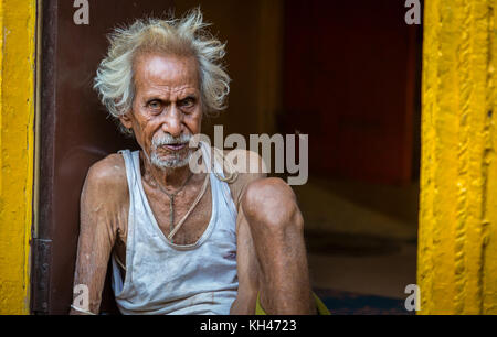 Close up of an old man sitting at his doorway in an alley at Varanasi, India. Stock Photo