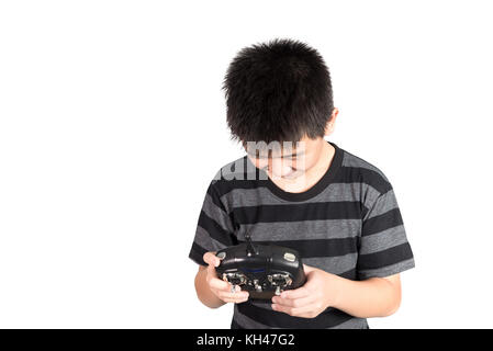 Asian boy holding radio remote control (controlling handset) for helicopter, drone or plane, studio shot isolated on white background. Stock Photo