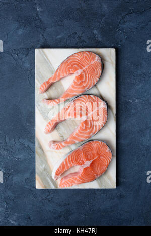 Uncooked salmon steaks on marble background. Top view, vertical, copy space for text. Concept of dieting, healthy eating, healthy lifestyle Stock Photo