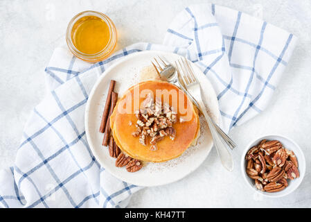 Pancakes with pecan nuts and honey on white plate. Table top view, horizontal composition Stock Photo