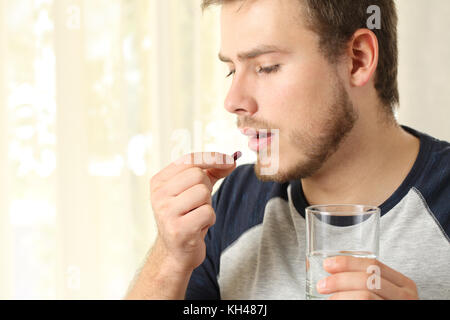 Serious man taking a pill standing at home Stock Photo