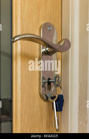Close up of keys in wooden internal door of house Stock Photo